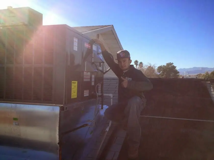 HVAC technician performing AC Tune-Up on a rooftop unit in Janesville